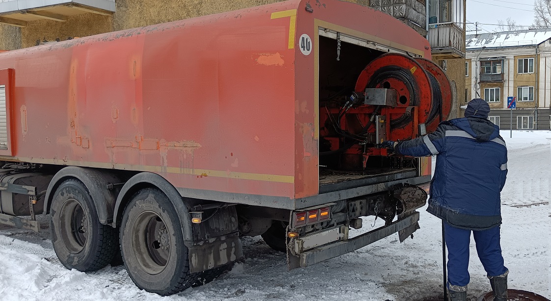 Каналопромывочная машина и работник прочищают засор в канализационной системе в Оленегорске